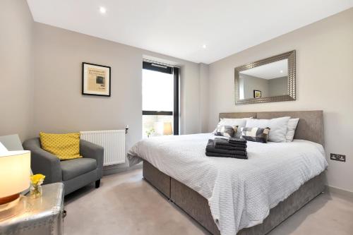 um quarto com uma cama, uma cadeira e um espelho em Esquire Apartments Ealing em Londres