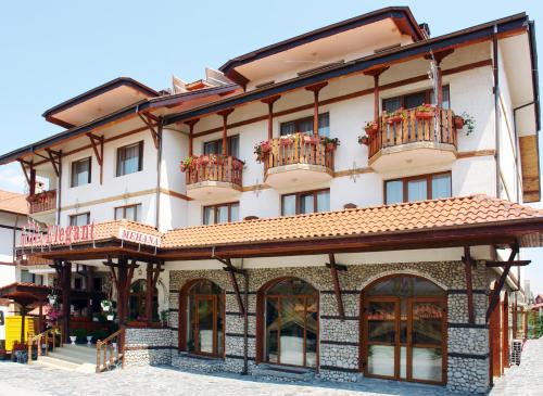 a large white building with balconies on a street at Elegant Hotel in Bansko