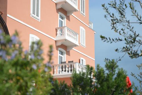 un edificio con balcones y árboles en el primer plano en Hotel Fiesa, en Piran