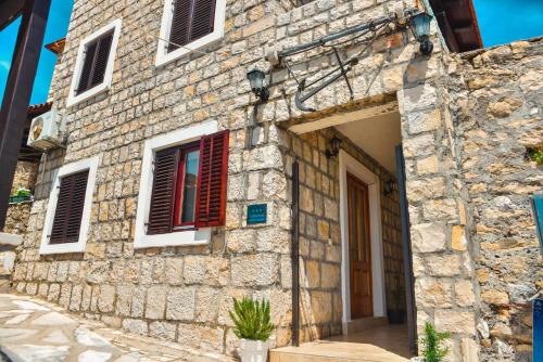 a stone house with red shutters on a building at Villa Marinero in Ulcinj