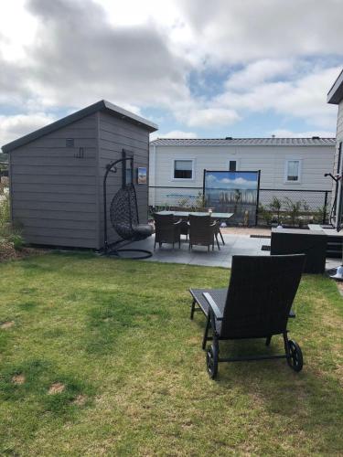 een tuin met een gebouw en een stoel in het gras bij Chalet SOL Y MAR in Renesse