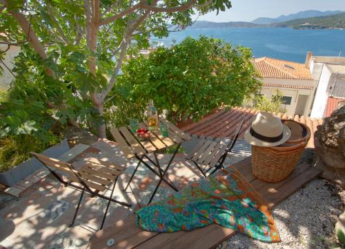 a table and chairs with a hat sitting on a deck at Sto Roloi Island Houses in Poros