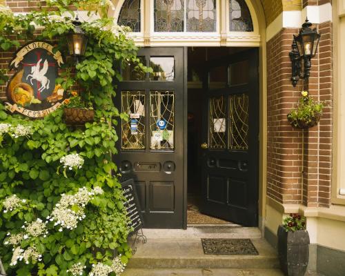 een zwarte voordeur van een huis met bloemen bij Hotel Pegasus in Apeldoorn