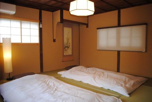 ein Schlafzimmer mit einem weißen Bett mit einer Lampe und einem Fenster in der Unterkunft NARAigoto EENA HOUSE in Nara