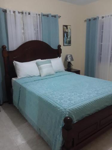 Schlafzimmer mit einem Bett mit blauer Decke in der Unterkunft Barrianna Villa in Montego Bay