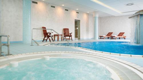 uma grande piscina com cadeiras num quarto de hotel em OREA Spa Hotel Cristal em Mariánské Lázně