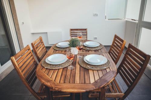 a wooden table with chairs and plates and wine glasses at Terradamare in Monopoli