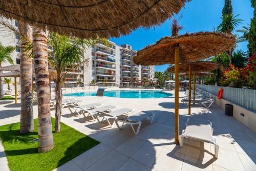 un complejo con una piscina con sillas y sombrillas en Rentalmar Navarra family suites, en Salou