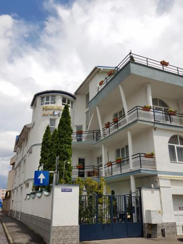 un bâtiment blanc avec un panneau bleu devant lui dans l'établissement Pensiunea Leo, à Braşov