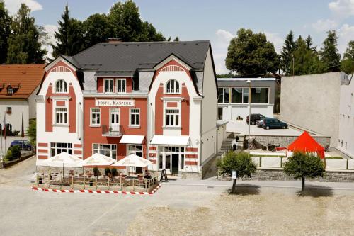 a building with tables and umbrellas in front of it at Hotel Kašperk in Kašperské Hory