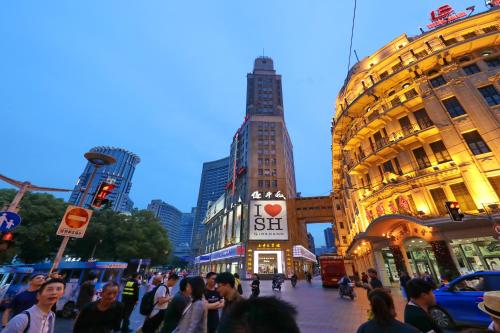 Eine Menschenmenge, die eine belebte Stadtstraße entlangläuft in der Unterkunft Seventh Heaven Hotel in Shanghai