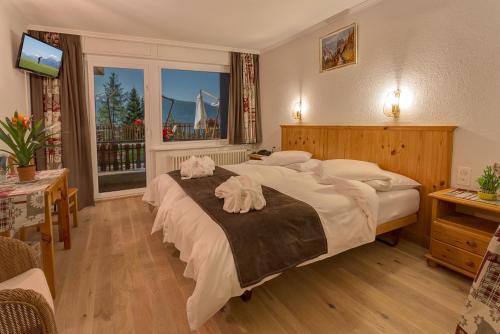 een slaapkamer met 2 bedden en handdoeken bij Hotel Ad'Eldorado in Crans-Montana