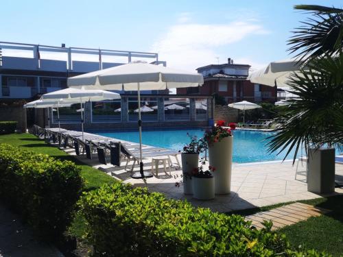 - une piscine avec des parasols et des chaises dans l'établissement Albergo Mediterraneo, à Terracine