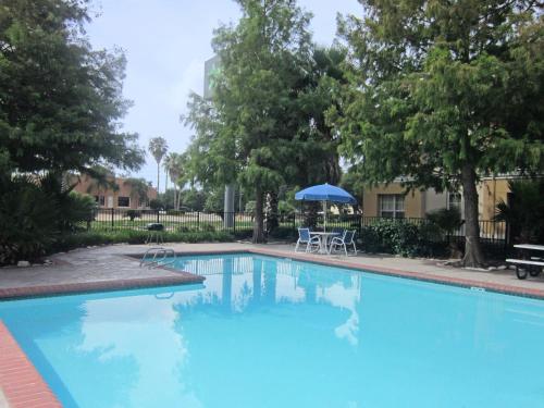 uma piscina azul com uma mesa e um guarda-chuva em Sonesta Simply Suites Stafford em Stafford