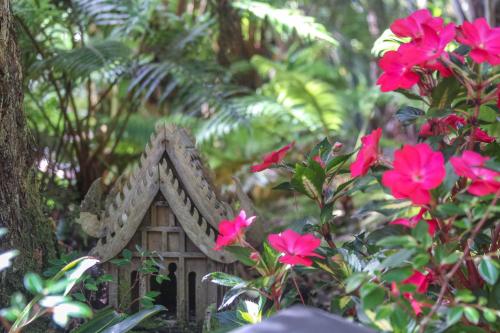 ein kleines Haus in einem Garten mit rosa Blumen in der Unterkunft At the Craters Edge in Volcano