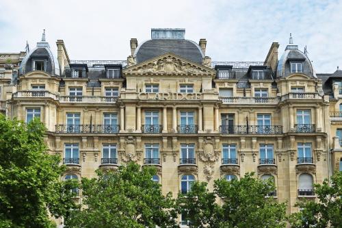 um edifício antigo em Paris com árvores à frente em Fraser Suites Le Claridge Champs-Elysées em Paris