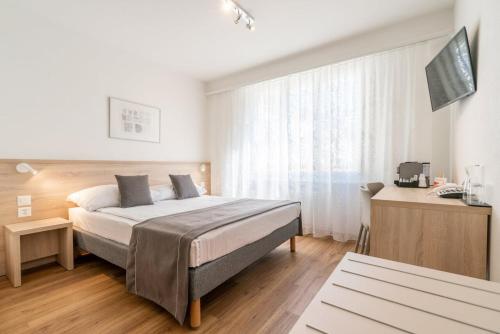 - une chambre avec un lit et une télévision dans l'établissement Hôtel Des Arts, à Neuchâtel