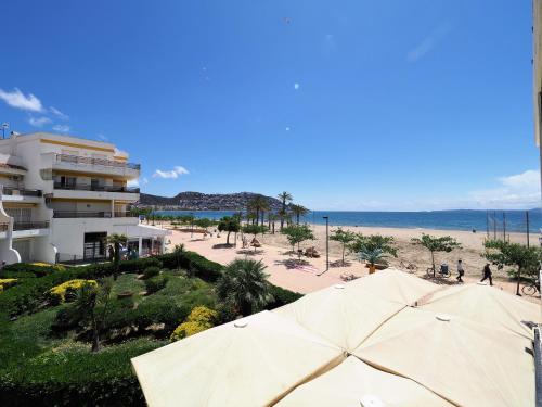 a beach with umbrellas in front of a building at InmoSantos Oasis A3 in Roses