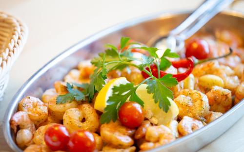 a bowl of food with shrimp and tomatoes on a table at Komforthotel Butjadinger Tor in Nordenham