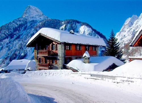 um edifício coberto de neve com montanhas ao fundo em Hotel Dente Del Gigante em Courmayeur