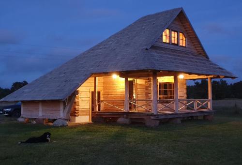 a large log cabin with a dog laying in the grass at Lāču namiņš/Bear house in Liepāja