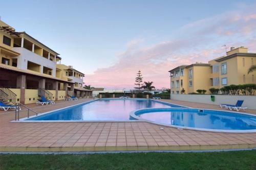 uma piscina em frente a alguns edifícios em Vilamoura Condominio do Pinhal em Vilamoura