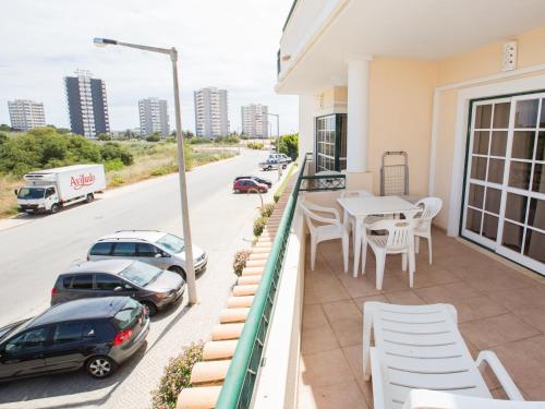 a balcony with white chairs and a table and cars at Apartamentos Quinta da Praia in Alvor