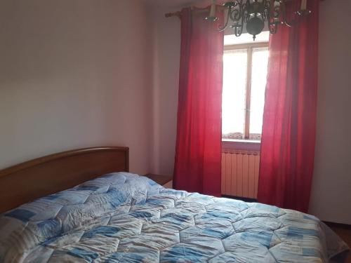 una camera con letto e finestra con tende rosse di Casa Cippilippi a Saint Vincent