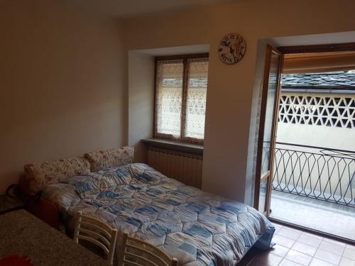 una camera con letto e balcone con orologio di Casa Cippilippi a Saint Vincent