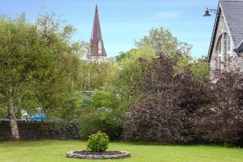 un giardino con chiesa e torre sullo sfondo di Fado Cottage Kenmare a Kenmare