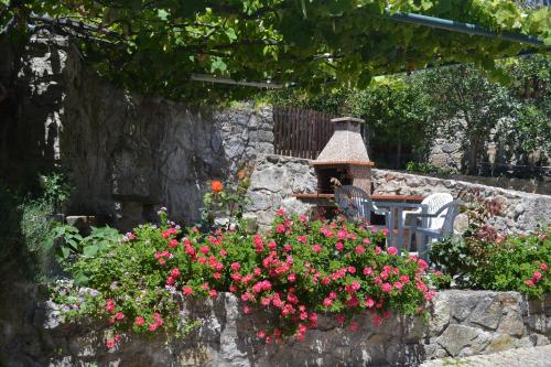 un jardin avec des fleurs roses et un mur en pierre dans l'établissement Quinta do Real - Casa de Campo, à Viana do Castelo