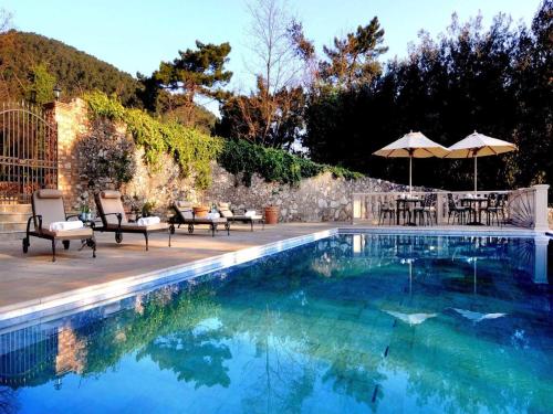 einen Pool mit Stühlen und Sonnenschirmen neben einer Wand in der Unterkunft Hotel Villa Casanova in Lucca