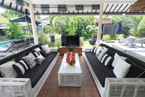 een patio met zwart-wit meubilair en een tv bij Villa Bloom 1 - 4 bedrooms, 4 bathrooms, private pool close to the beach in Seminyak