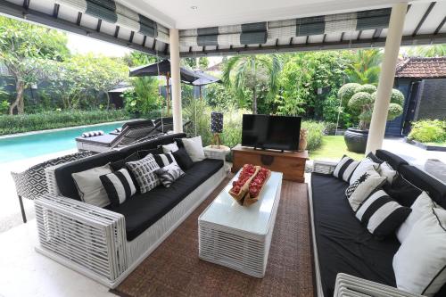 een afgeschermde veranda met een bank en een tv bij Villa Bloom 1 - 4 bedrooms, 4 bathrooms, private pool close to the beach in Seminyak