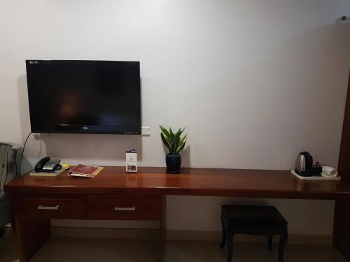 escritorio de madera con TV en la pared en PADDY'S HOTEL & APARTMENTS, en Port Moresby