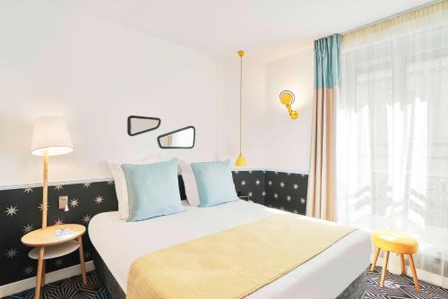 a bedroom with a large bed with blue pillows at Hôtel Augustin - Astotel in Paris