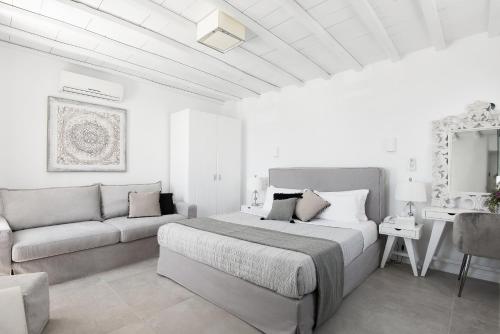 een witte slaapkamer met een bed en een bank bij Riva Suites - Adults Only in Mykonos-stad