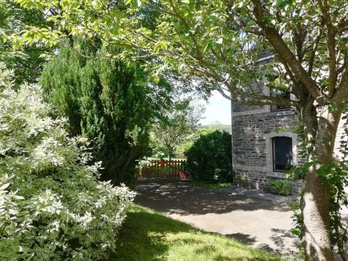 un jardín con un edificio de piedra y árboles en Au bord de l'Eau, en Bastogne