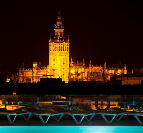 een groot gebouw met 's nachts een klokkentoren bij Hotel Don Paco in Sevilla