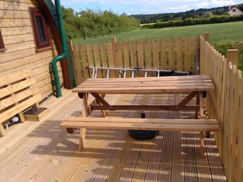 un banc en bois assis sur une terrasse à côté d'une clôture dans l'établissement shanagarry / Ballycotton Glamping pod, à Cork