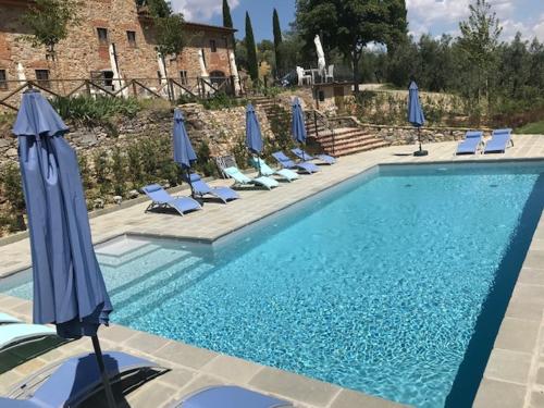 een zwembad met blauwe parasols en ligstoelen bij Agriturismo San Martino in Quarrata