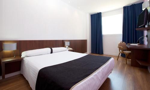 - une chambre avec un lit, un bureau et un ordinateur dans l'établissement Hotel Olympia Universidades, à Valence