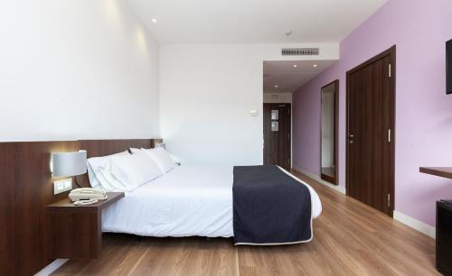 une chambre d'hôtel avec un lit et un téléphone dans l'établissement Hotel Olympia Universidades, à Valence