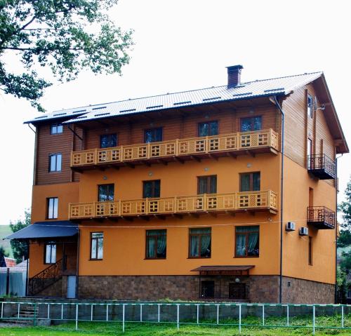 un grand bâtiment orange avec des balcons en bois dans l'établissement Hotel Forward Pool&Sauna, à Yasinya