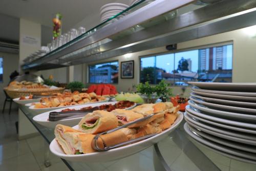 una línea de buffet con sándwiches y platos de comida en Turis Hotel Centro, en Campo Grande