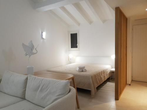 Cette chambre blanche dispose d'un lit et d'un canapé. dans l'établissement Résidence les Hameaux de Bocca del Oro, à Porto-Vecchio