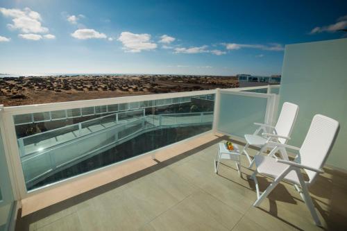 a balcony with two chairs and a view of the beach at Hotel Boutique TAO Caleta Mar in Corralejo