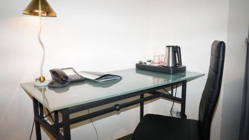 a desk with a lamp and a telephone on it at Entrée Groß Borstel Garni Hotel in Hamburg