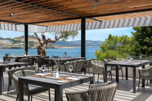 um restaurante com mesas e cadeiras e vista para a água em Lindos Mare, Seaside Hotel em Líndos