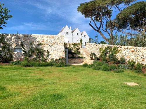 un mur en briques avec une maison blanche derrière elle dans l'établissement Masseria Grofoleo, à Locorotondo